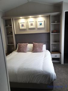 um quarto com uma cama com lençóis brancos e almofadas em Modern Sea View Holiday Home Isle of Wight em Porchfield