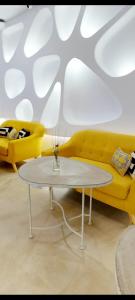 een woonkamer met een gele bank en een tafel bij Hotel Boutique Suite Generis, Premiado El hotel más acogedor de España in Córdoba
