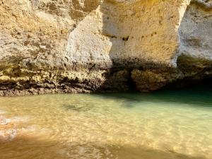 a body of water next to a rocky cliff at Albufeira Oldtown 330ft Beach Private garage AC Wifi in Albufeira