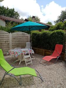due sedie e un tavolo con ombrellone di La girolle a Hourtin