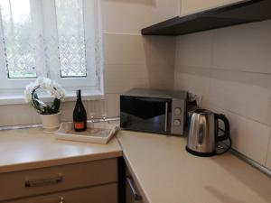 a kitchen counter with a microwave and a bottle of wine at Leśny Apartament II in Szczytno