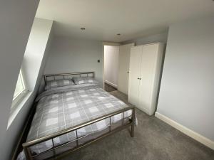 1 dormitorio con cama y pared blanca en 3 bed Apartment in Colliers Wood en Londres