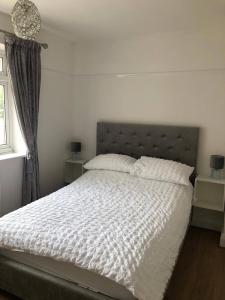 ein Schlafzimmer mit einem Bett mit weißen Laken und einem Fenster in der Unterkunft 3 bed bungalow Penrhyn Bay Llandudno in Llandrillo-yn-Rhôs
