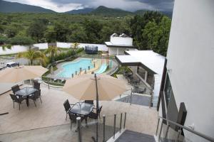 an outdoor patio with a pool and tables and umbrellas at La Terraza Hotel in Jalpan de Serra