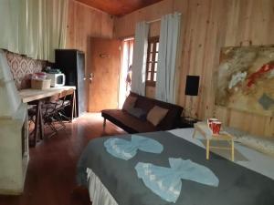 坎波斯杜若尔当Villa Valentina chalés com lareira e churrasqueira的一间卧室配有一张床,客厅配有书桌