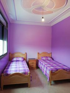 duas camas num quarto com paredes roxas em Appartements proches de la mer Boukidan Al Hoceima em Al Hoceïma
