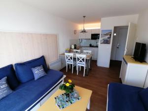 a living room with a blue couch and a kitchen at Cap Morgat chez Jean in Crozon