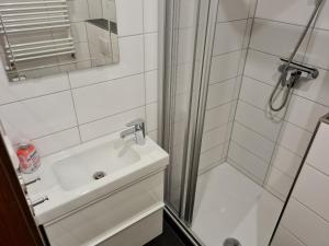 a white bathroom with a shower and a sink at Bergstation Altenau in Altenau