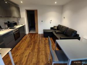 a living room with a black couch and a kitchen at Earl Street124 in Sheffield