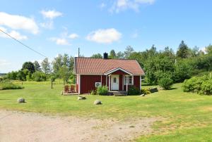 a small red house on a grassy field at Hustugu Gård in Örsundsbro