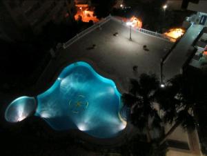Una piscina de noche con una piscina azul. en Viva Sky Benidorm, en Benidorm