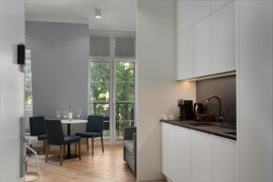 uma cozinha com armários brancos e uma mesa com cadeiras em Villa 44 -V44- em Świnoujście