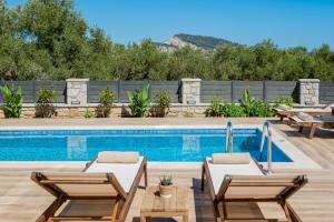 a swimming pool with two lounge chairs next to a swimming pool at Villa Olive Green in Argassi