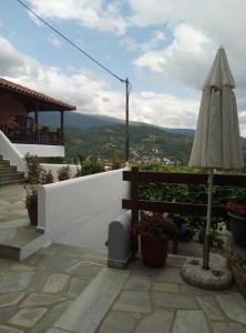 eine Terrasse mit einem Sonnenschirm, einem Stuhl und einem Sonnenschirm in der Unterkunft Guesthouse Kallisti in Anilio Pelion