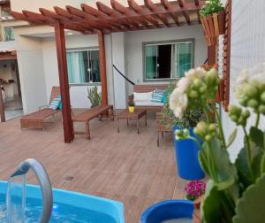 d'une terrasse avec des bancs, une table et des chaises. dans l'établissement Casa com Piscina e Churrasqueira e excelente Localização em Piuma, à Piúma