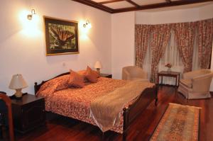 a bedroom with a bed and two chairs at Cocoon Hills in Nuwara Eliya