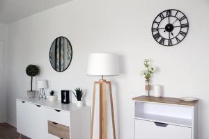 a living room with a clock on the wall and a lamp at Cabourg - Studio cosy à 1 min de la plage in Cabourg +18 photos