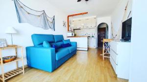 sala de estar con sofá azul y cocina en Cozy beach-front studio with amazing sea view, en Empuriabrava