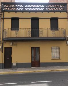 un edificio amarillo con balcón en una calle en Hostal Sant Marti premium, en Puig-reig