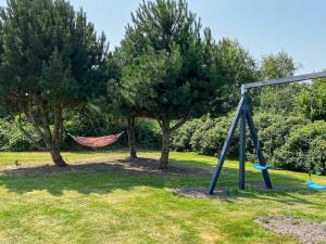 a hammock in a park with two trees at 6 person holiday home in Hadsund in Øster Hurup