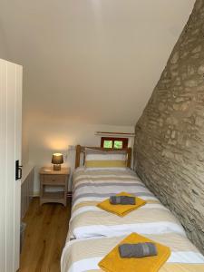 a bedroom with two beds and a stone wall at Glyncoch Aberporth in Aberporth