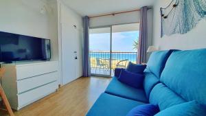 sala de estar con sofá azul y TV en Cozy beach-front studio with amazing sea view, en Empuriabrava