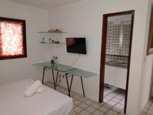 um quarto com uma mesa, uma televisão e uma cama em Flat no hotel fazenda portal de Gravatá em Gravatá