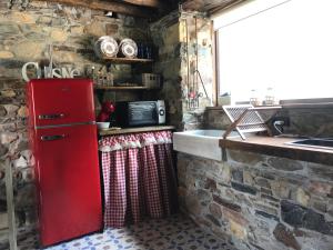 cocina con nevera roja en una pared de piedra en El Horreo deI Sol, en Trevías