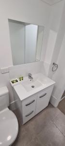 a bathroom with a sink, toilet and mirror at Chasely Apartment Hotel in Brisbane