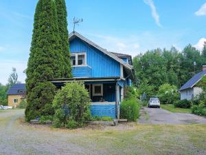 a blue house with a large tree at 6 person holiday home in MARIESTAD in Mariestad