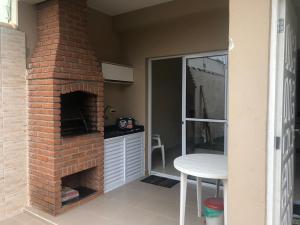 una chimenea de ladrillo en una cocina con mesa en Linda Casa pé na areia em Mongagua, en Mongaguá 4 fotos más