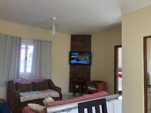 Una sala de estar con un sofá y un televisor. en Linda Casa pé na areia em Mongagua, en Mongaguá