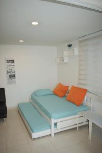 łóżko z pomarańczowymi i niebieskimi poduszkami w pokoju w obiekcie APARTAMENTO EN EL LAGUITO, CARTAGENA w mieście Cartagena de Indias