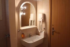a bathroom with a sink, mirror and bath tub at Hotel Kamari in Kamarai