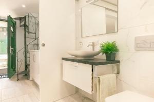 uma casa de banho branca com um lavatório e um espelho em Cosy Duplex House in Downtown Lisboa em Lisboa