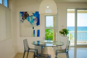 a dining room with a glass table and chairs at Whispering Seas Oceanfront Suite in Ocho Rios