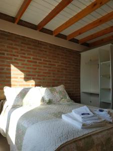 a bedroom with a bed and a brick wall at Masia del Valle in Trevelín