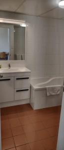 a bathroom with a sink and a tub and a mirror at Chasely Apartment Hotel in Brisbane