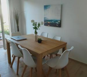 a dining room table with white chairs and a laptop on it at LA MAISON BLEUE, à 20 mn de Strasbourg, sur la route des vins, jusqu'à 6 personnes, Sélestat in Sélestat