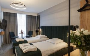 a hotel room with two beds and a room with two chairs at Hotel Alexander in Kraków