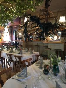 une salle à manger avec des tables et des nappes blanches dans l'établissement Murmeltier, à Hausen im Tal