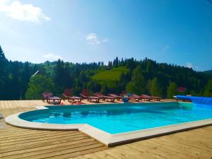 einen Pool auf einer Holzterrasse mit Tischen und Stühlen in der Unterkunft Plavianska Sadyba in Plavie