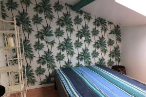 a bedroom with a mural of palm trees on the wall at Charmante maison dans la vallée de la Charente in Voulême