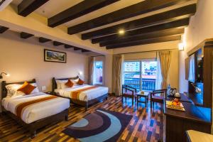a hotel room with two beds and a television at Hotel Kausi in Pokhara