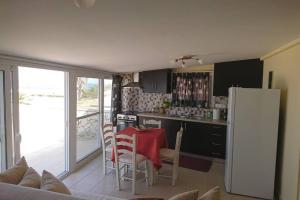 eine Küche mit einem Tisch und einem weißen Kühlschrank in der Unterkunft KORONI MARE -Sea view apartment/διαμέρισμα με θέα στην θάλασσα in Koroni