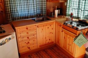 cocina con armarios de madera, fregadero y fogones en Hytte ved sjøen en Kristiansand