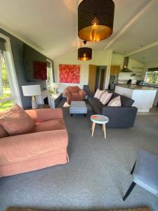 a living room with two couches and a table at Lovely Lodge in private grounds with enviable view in Hordle