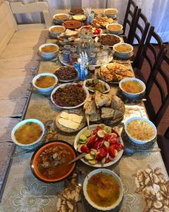 une longue table remplie de différents types de denrées alimentaires dans l'établissement Century House of Larisa, à Mestia