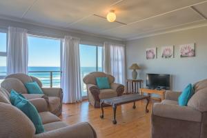 a living room with chairs and a television with a view of the ocean at No 52 Eersterivier Rd Tsitsikamma in Eersterivierstrand