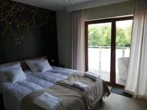 a bedroom with a bed and a large window at Apartament Latarnik- BIG in Gąski